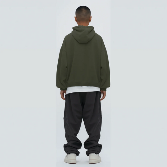 Person wearing a Olive green hoodie and black pants on a white background