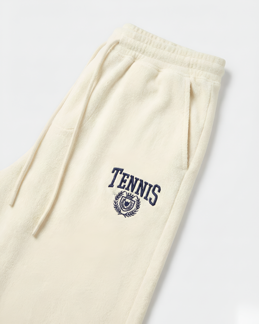 Beige sweatpants with 'Tennis' and crest design on a white background