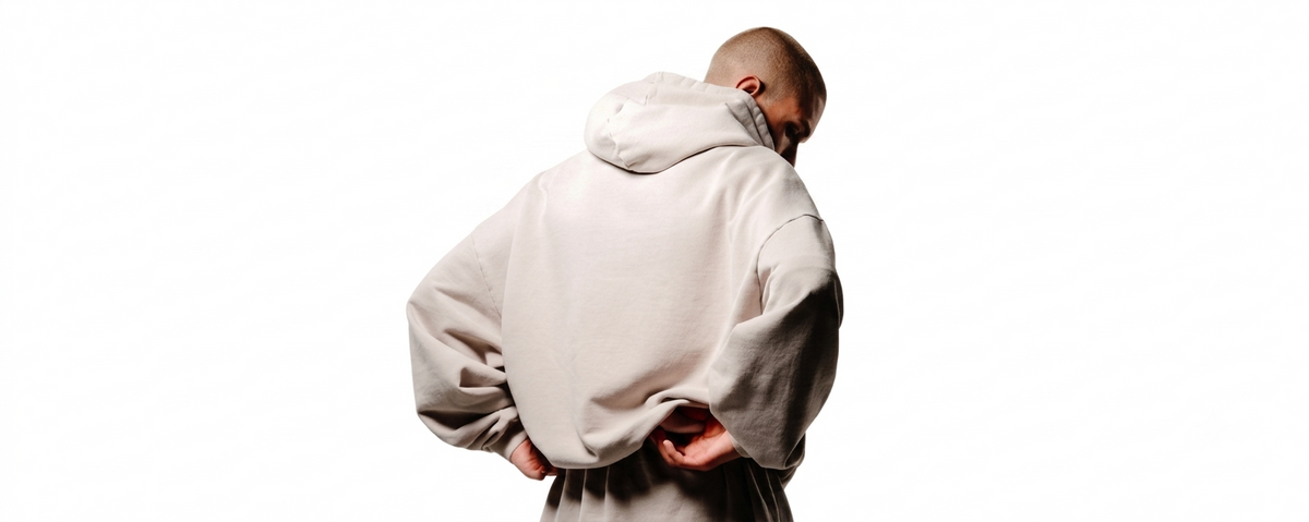 A person shown from behind wearing a light beige oversized hoodie and matching pants, standing against a plain white background.