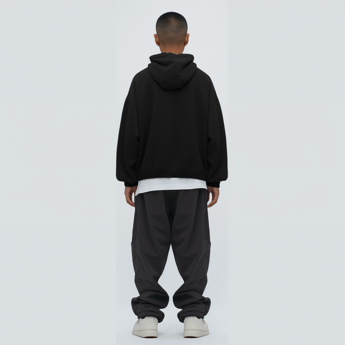 Person wearing a black hoodie and dark pants on a white background