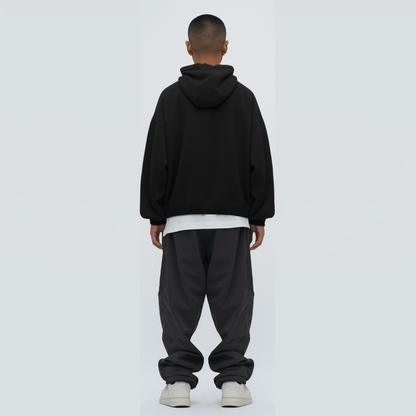 Person wearing a black hoodie and dark pants on a white background