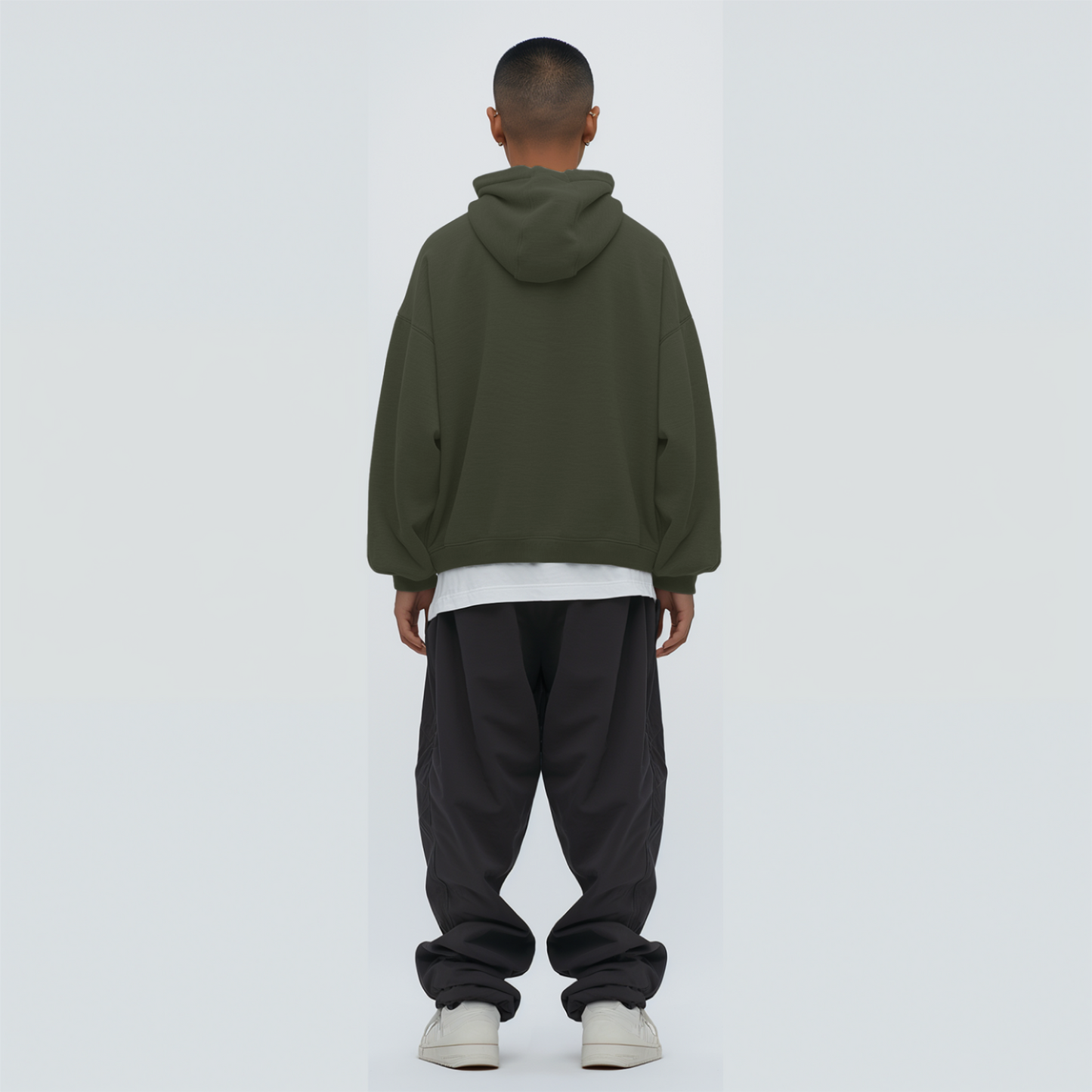 Person wearing a Olive green hoodie and black pants on a white background