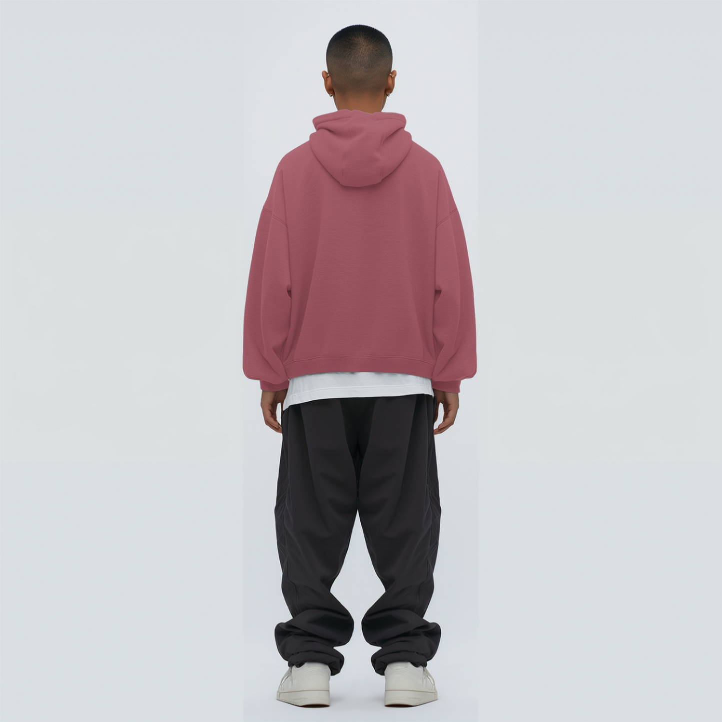Person wearing a coral hoodie and black pants on a white background