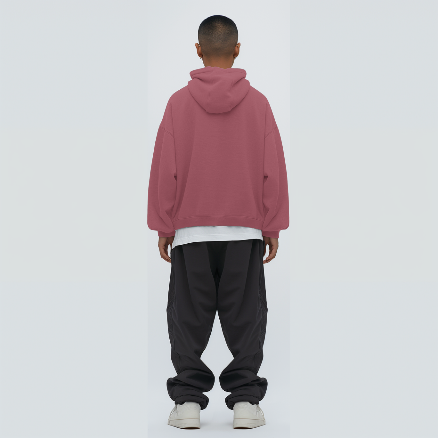 Person wearing a coral hoodie and black pants on a white background
