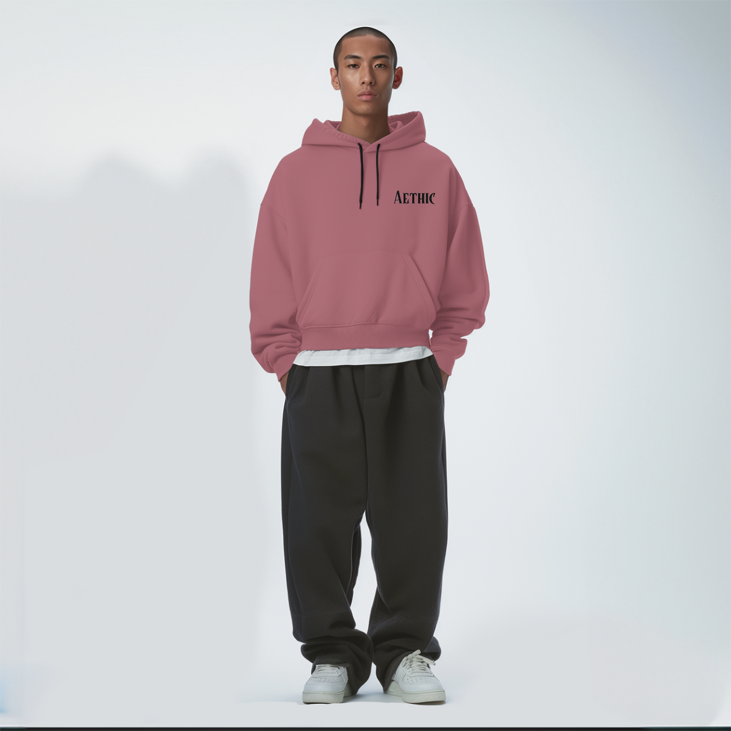 Person wearing a Coral hoodie with 'ATHIC' branding on a white background