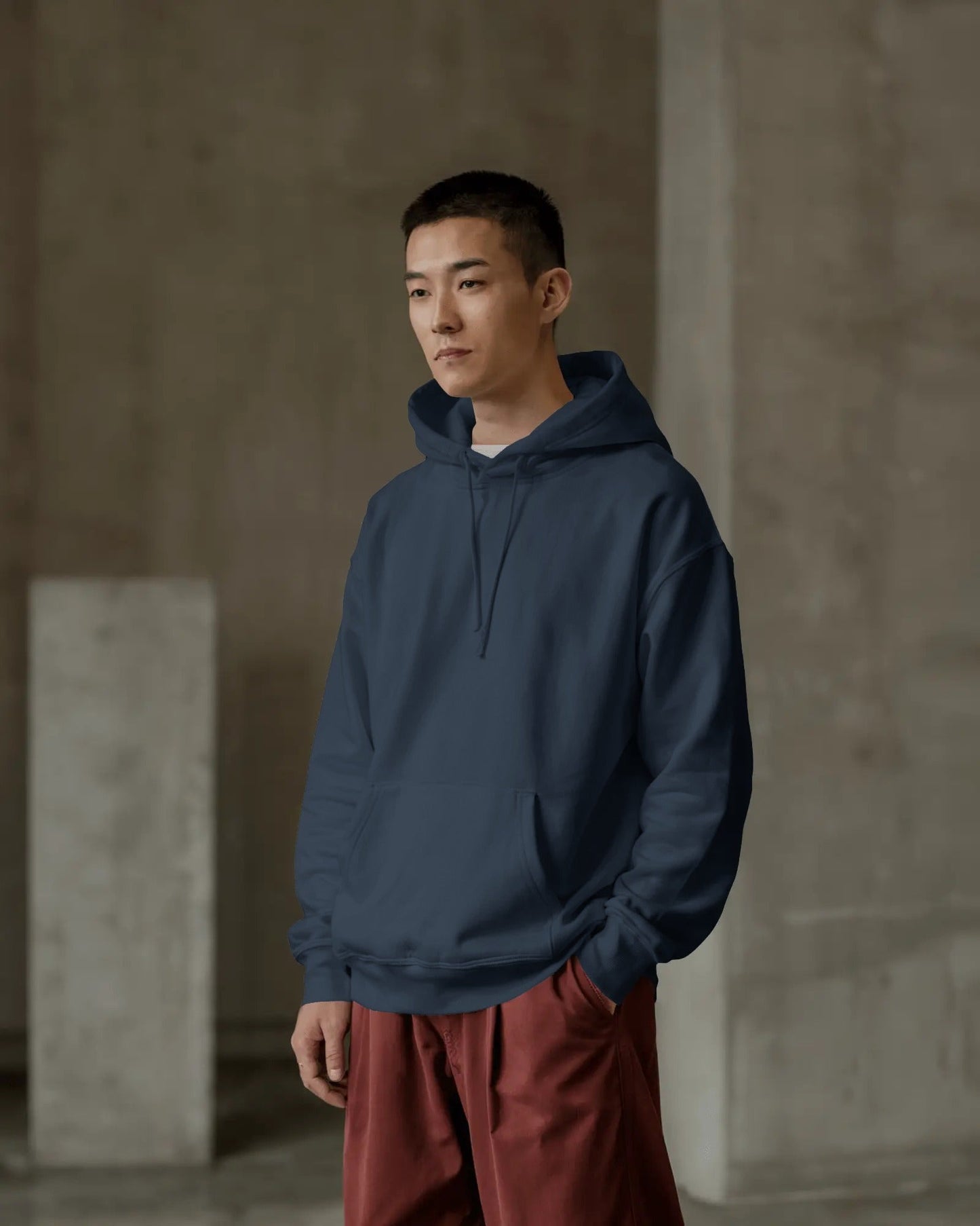 Person wearing a blue hoodie and red pants standing against a neutral background