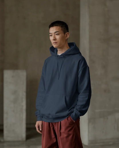 Person wearing a blue hoodie and red pants standing against a neutral background