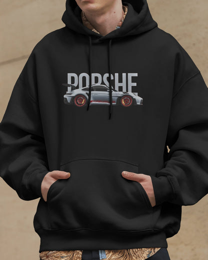 Person wearing a Colour_Black  hoodie with Porsche logo and car graphic on a beige background