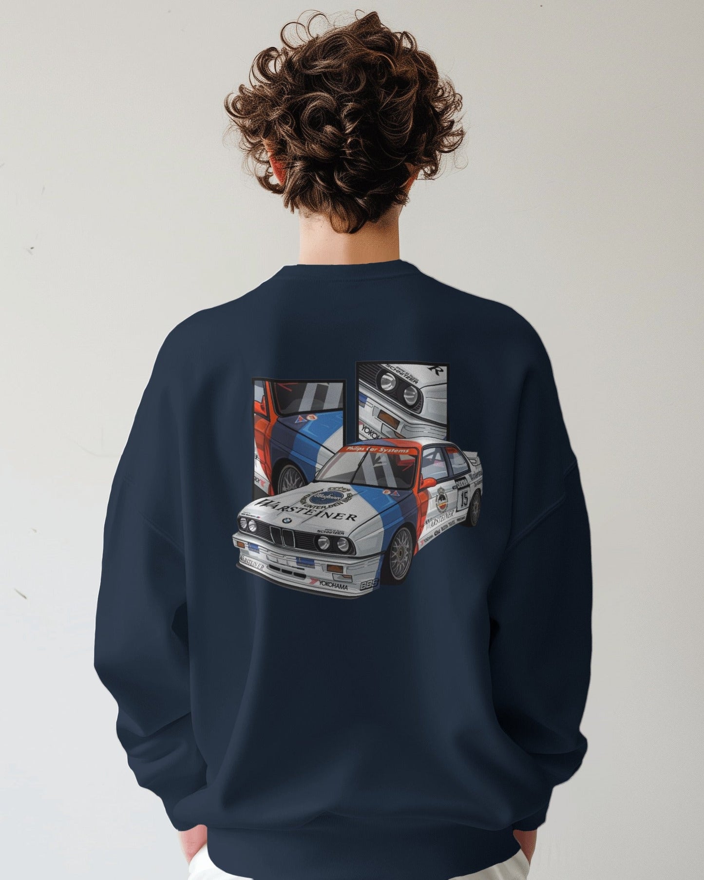 Person wearing a navy blue sweatshirt with a car graphic on the back against a white background