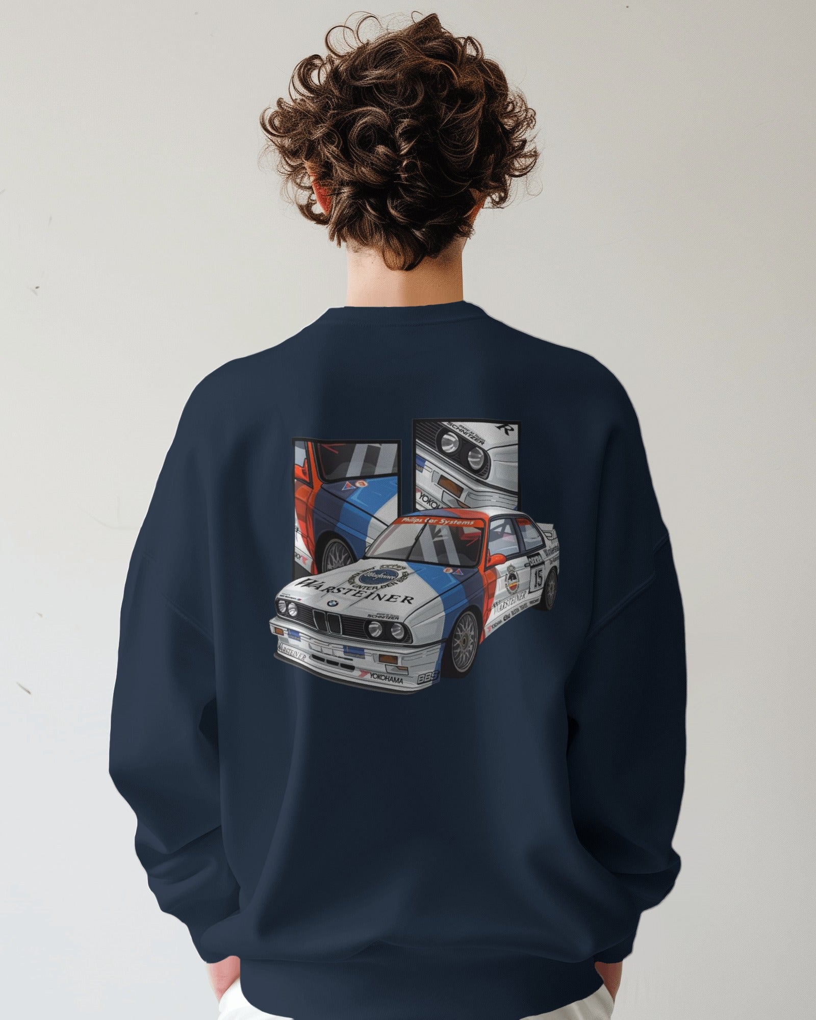 Person wearing a navy blue sweatshirt with a car graphic on the back against a white background