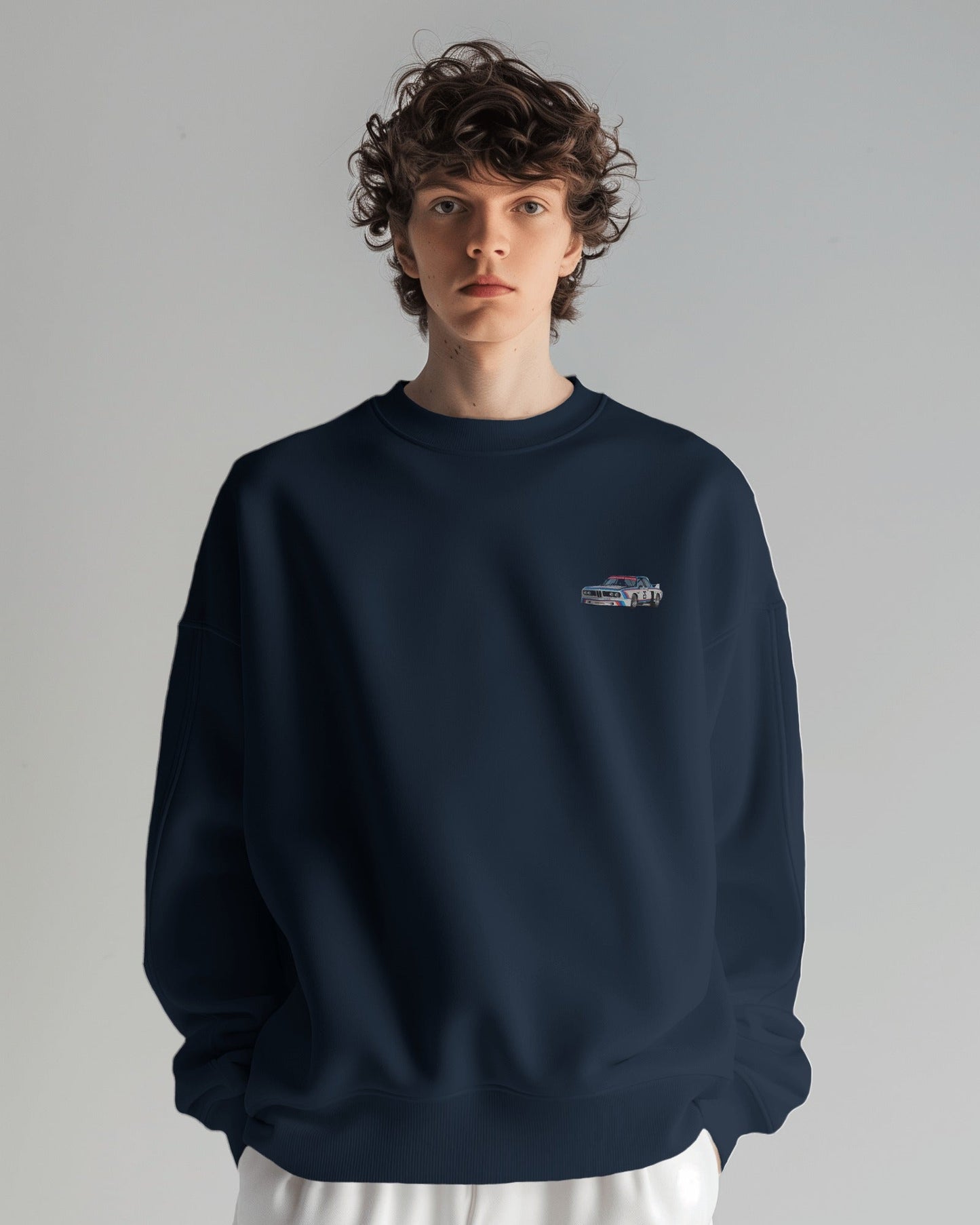 Person wearing a navy blue sweatshirt with a small logo on a gray background