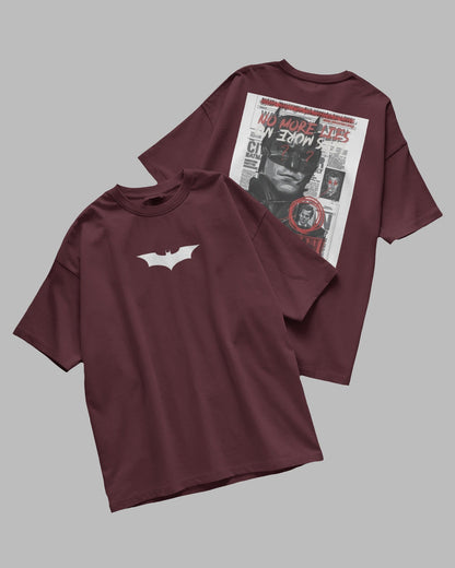Two maroon t-shirts, one with a white bat logo and the other with a graphic design on the back, on a gray background.