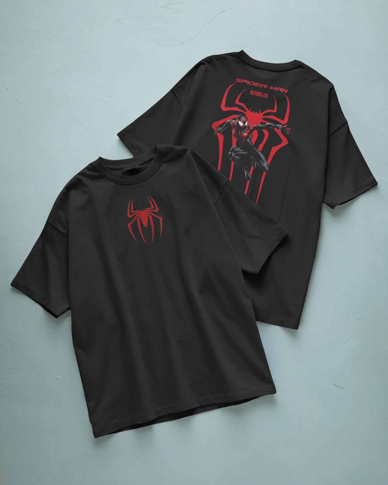 Two black t-shirts with red spider graphic on a light blue background