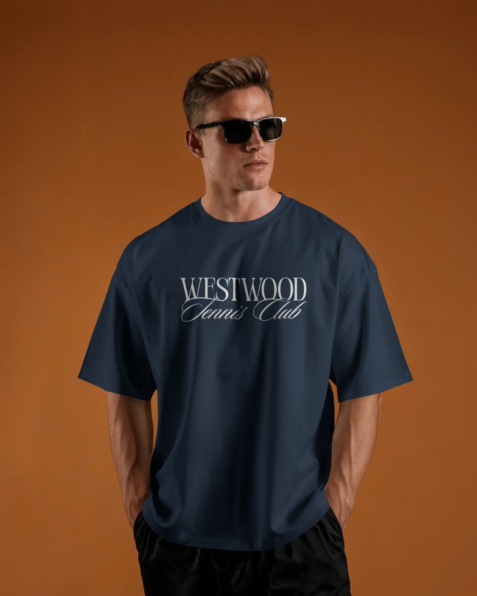 Man wearing a navy blue t-shirt with 'Westwood Tennis Club' text on an orange background