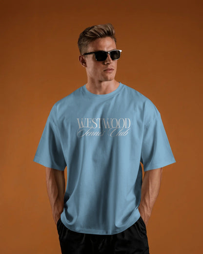 Man wearing a baby blue t-shirt with 'Westwood Club' text on an orange background