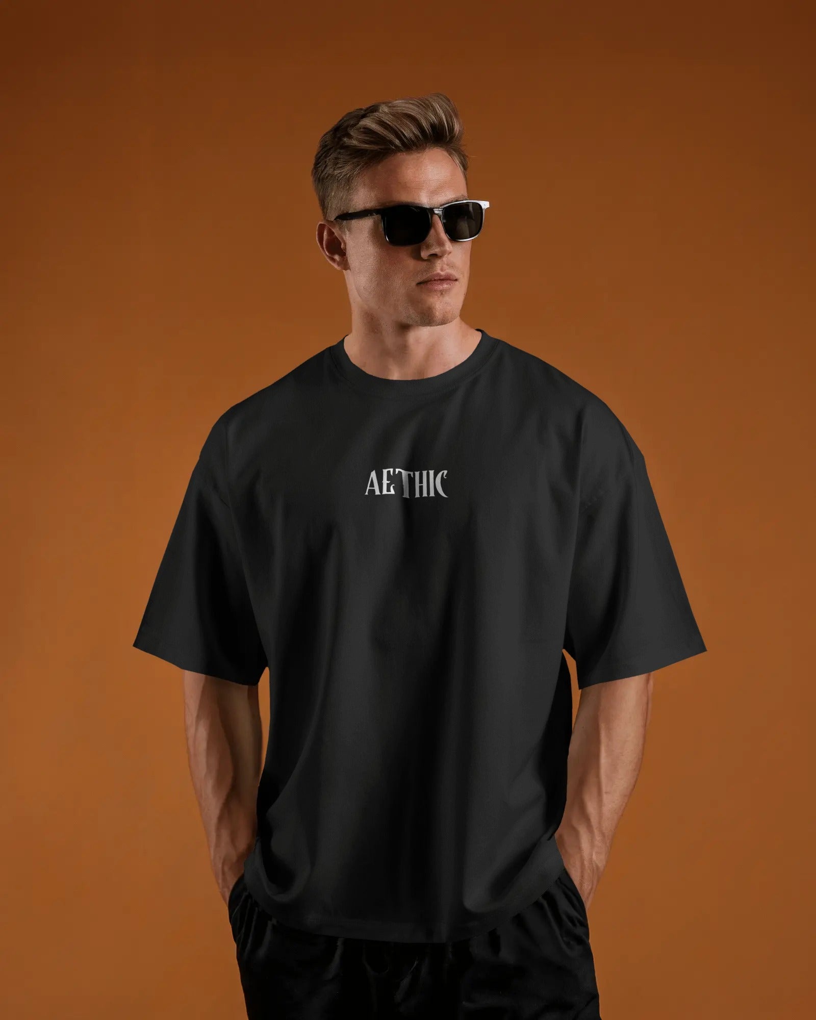 Man wearing a Colour_black t-shirt with 'Aethic' logo against an orange background