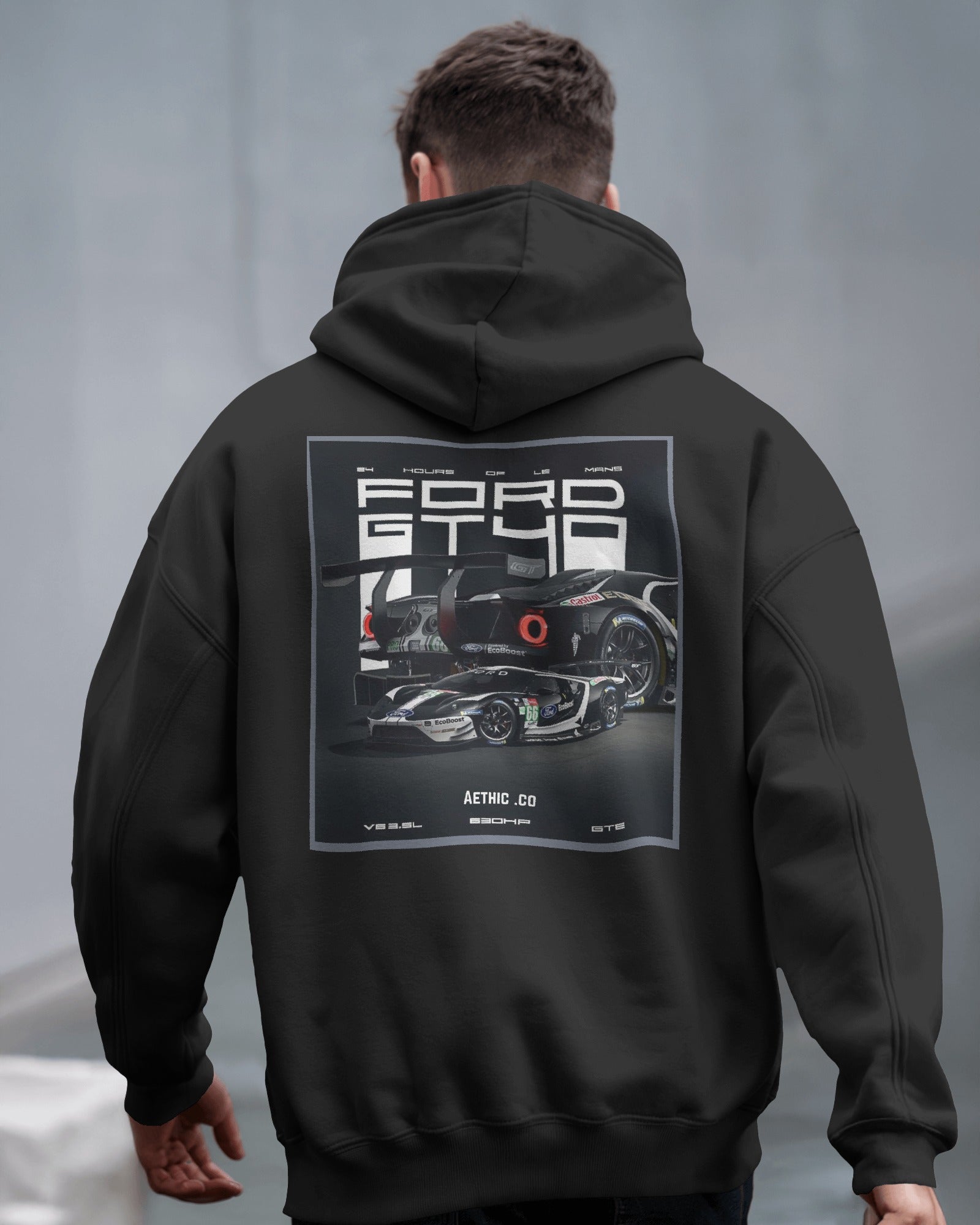 Person wearing a black hoodie with a Ford GT40 graphic on the back against a gray background
