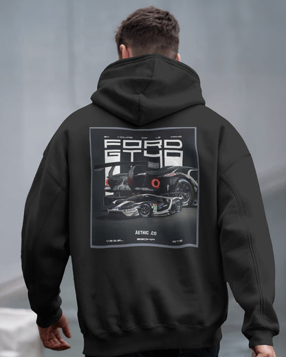 Person wearing a black hoodie with a Ford GT40 graphic on the back against a gray background