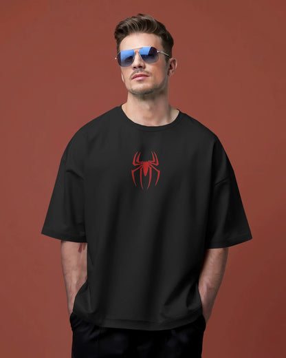 Man wearing a black t-shirt with a red spider logo against a brown background
