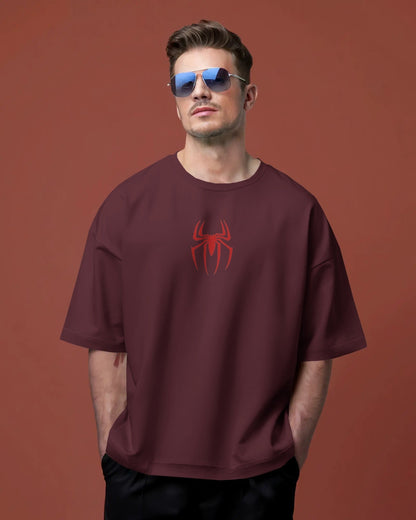 Man wearing a maroon t-shirt with a red spider logo against a brown background