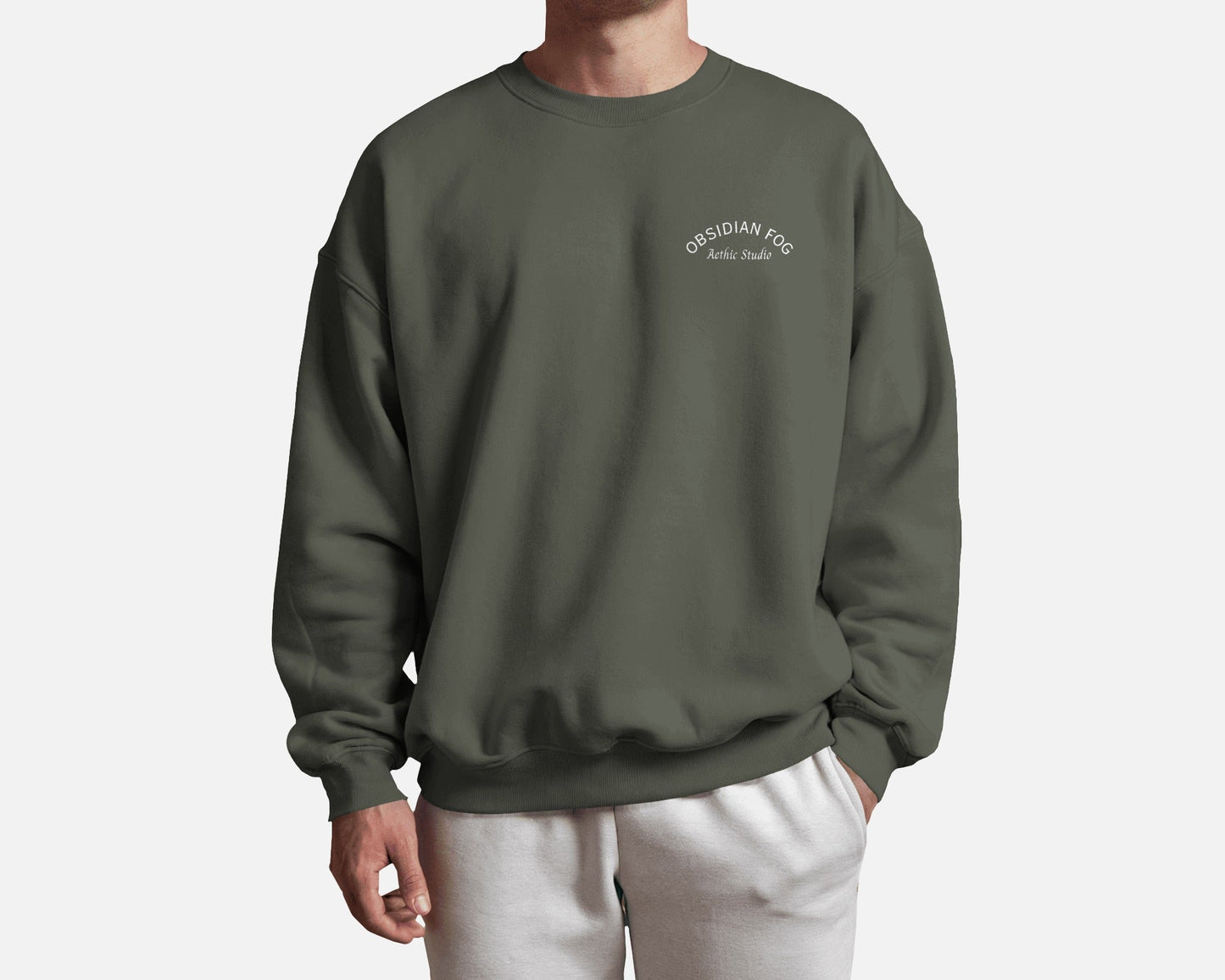 Male model wearing Obsidian Fog graphic sweatshirt in dark green color by Aethic Studios