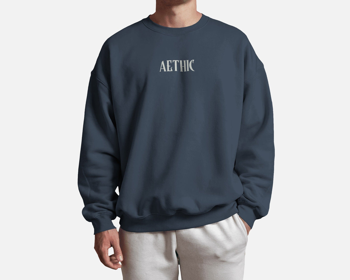Person wearing a navy blue sweatshirt with 'AETHIC' text on a white background