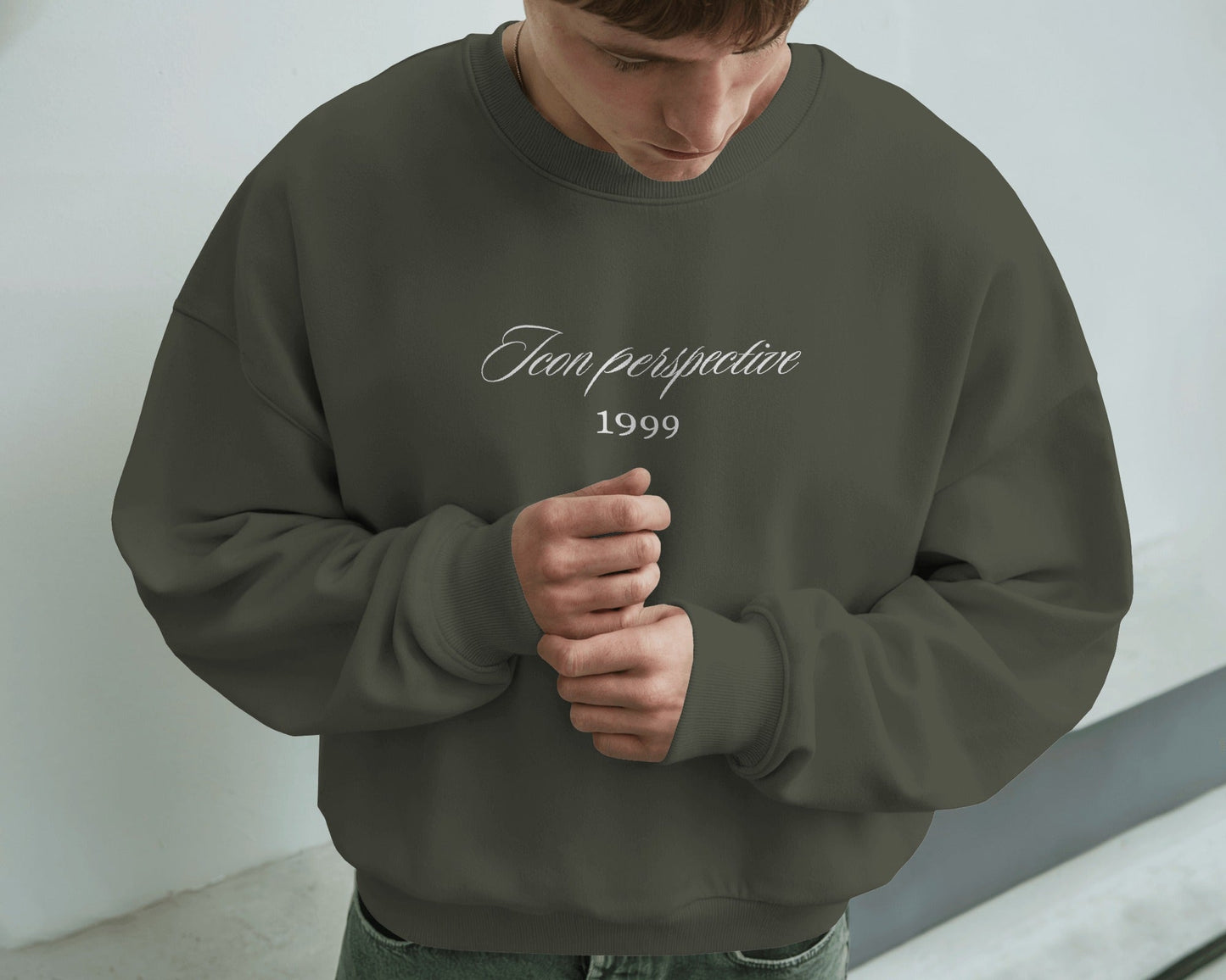 Person wearing a dark green sweatshirt with text, standing against a plain background