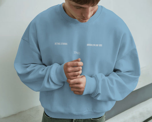 Person wearing a baby blue sweatshirt with text on a plain background