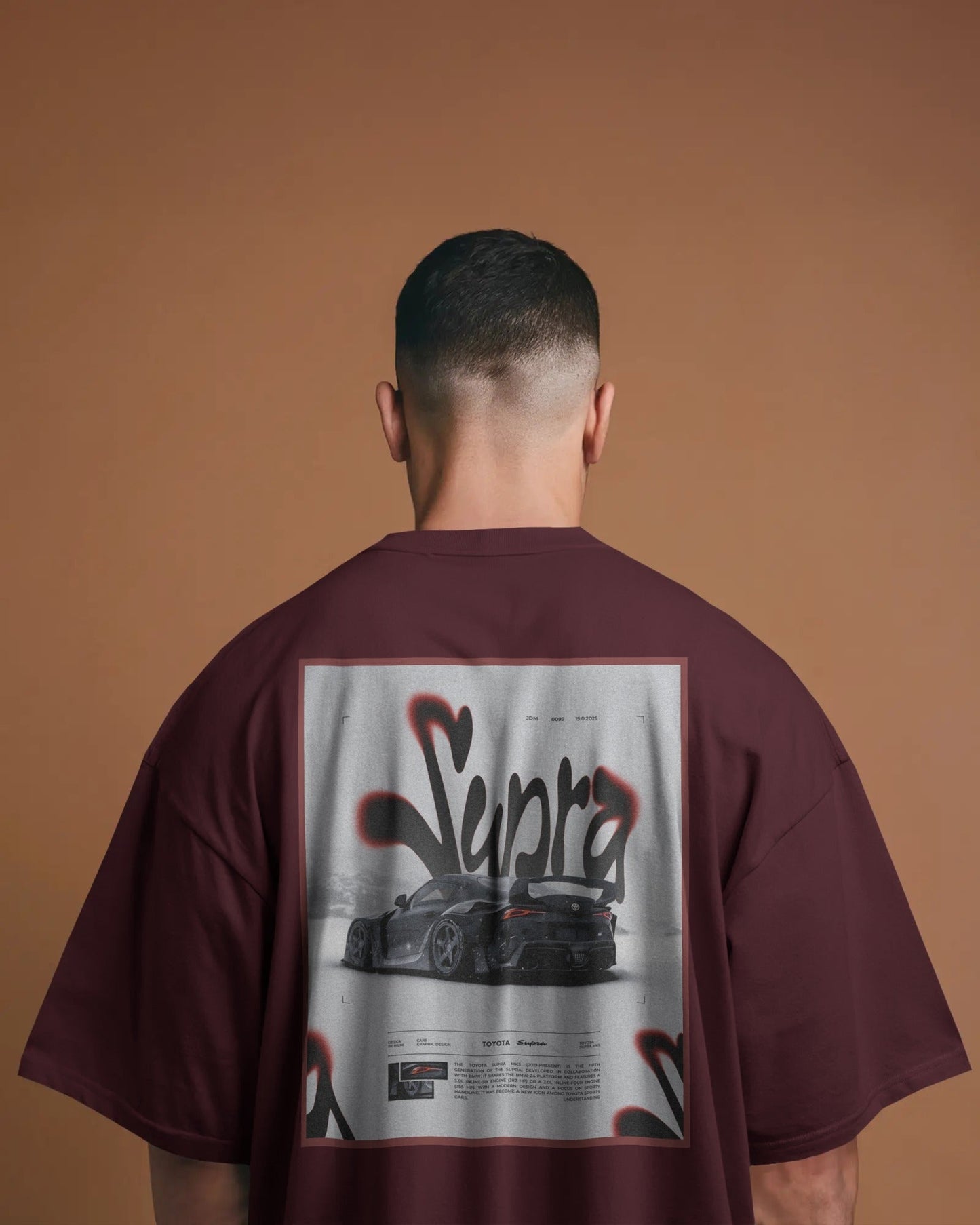 Person wearing a Colour_Maroon t-shirt with a graphic design on the back against a brown background