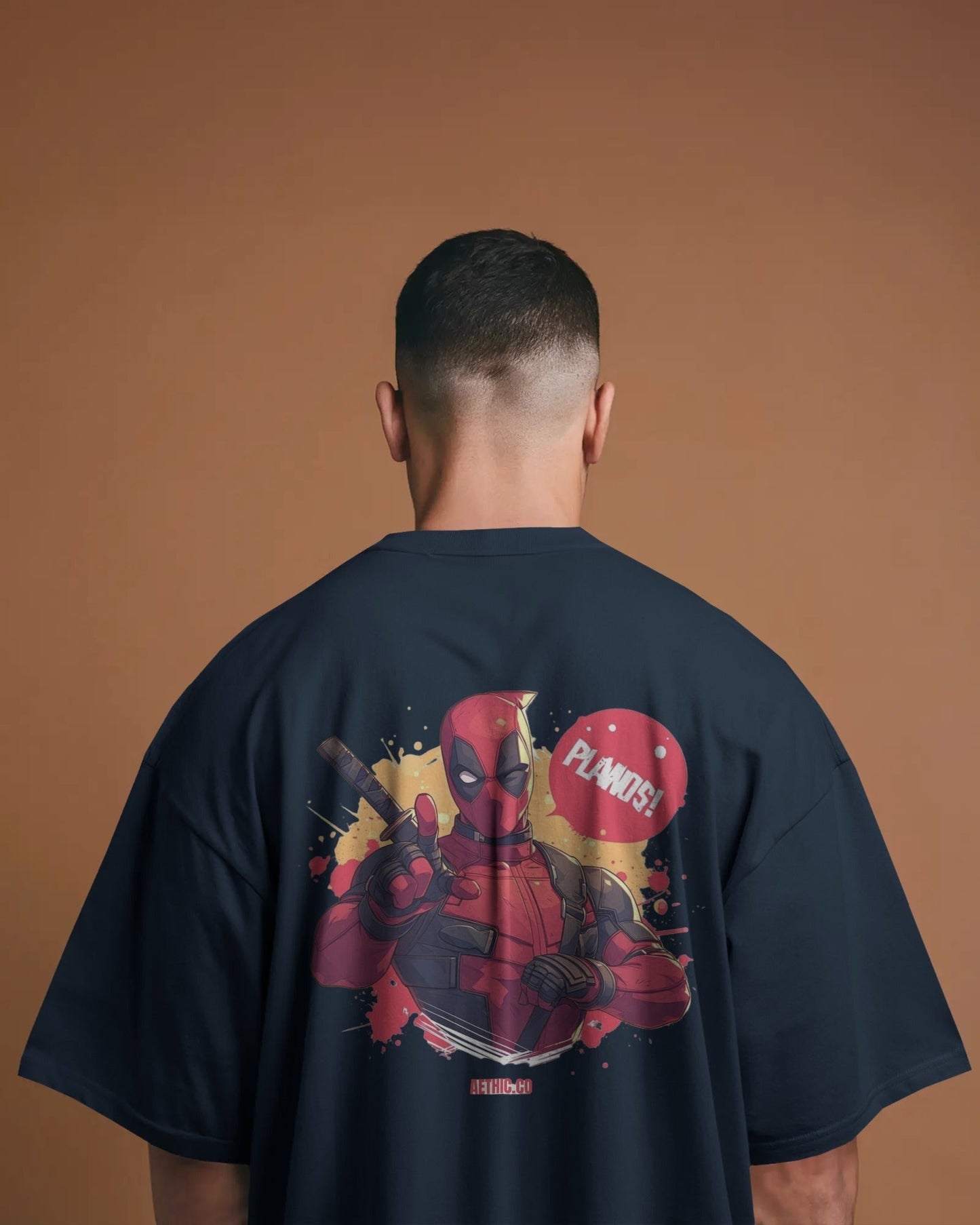 Person wearing a navy blue t-shirt with a Deadpool graphic on the back against a brown background
