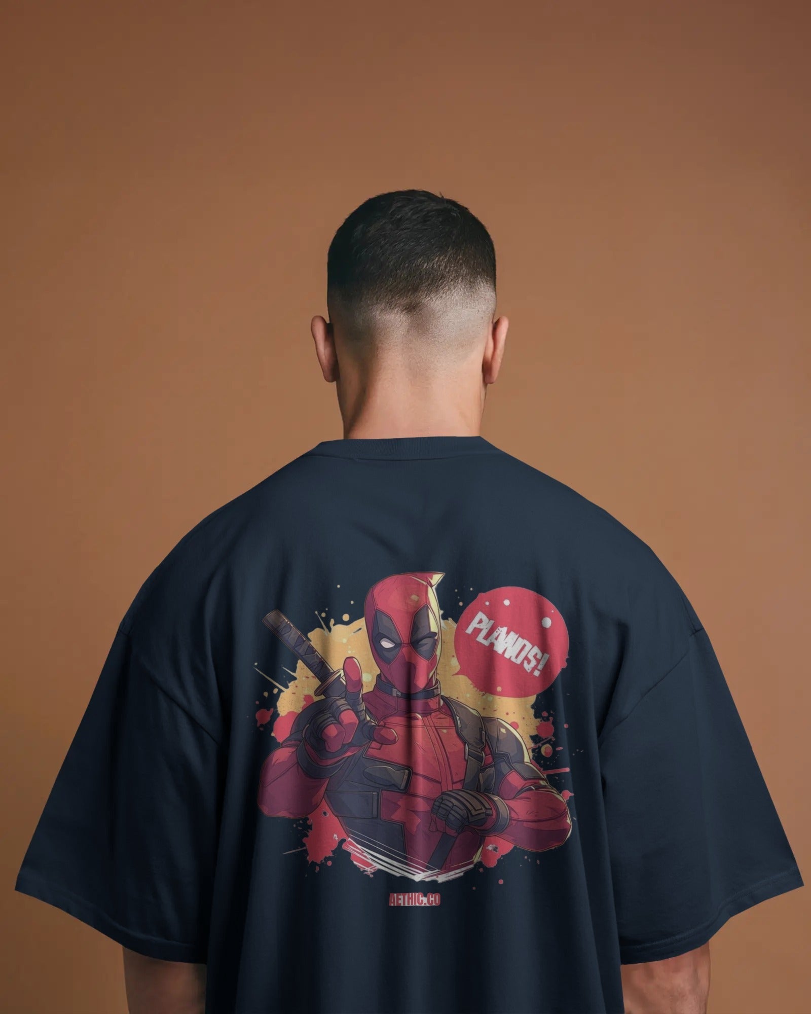 Person wearing a navy blue t-shirt with a Deadpool graphic on the back against a brown background