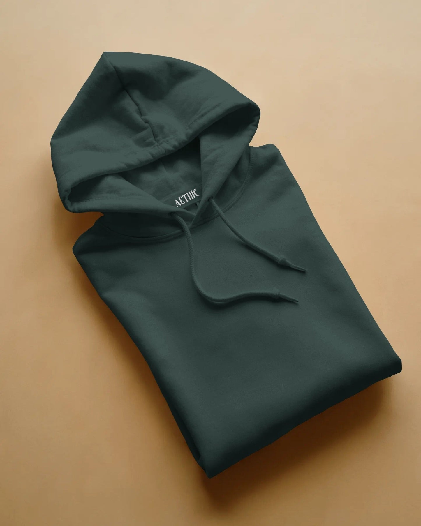 Folded dark green hoodie with 'ACTIK' branding on a beige background