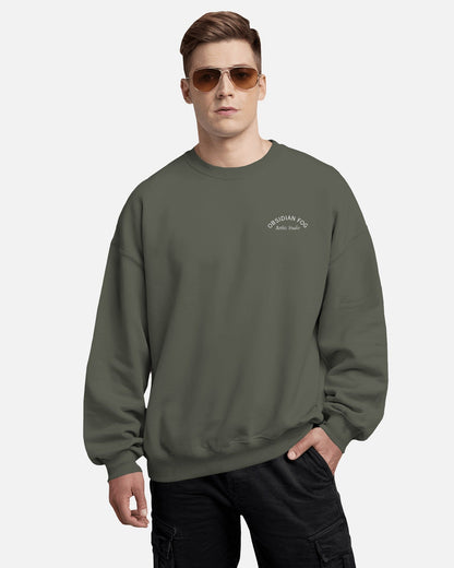Male model wearing Obsidian Fog graphic sweatshirt in dark green color by Aethic Studios