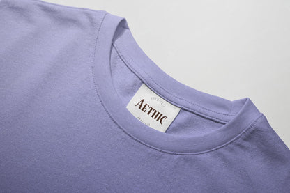Close-up of a purple shirt with a 'AETHIC' label on a light gray background